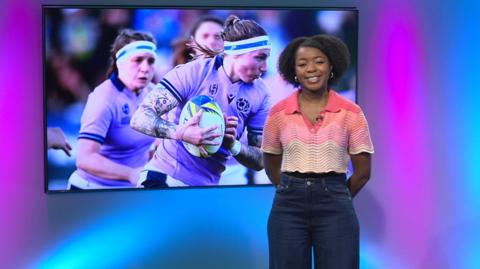Emma-Louise in the studio with rugby players in the screen