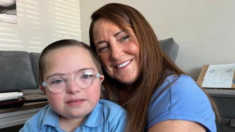 Jesse and his mum Vanessa, sitting on the floor both wearing blue