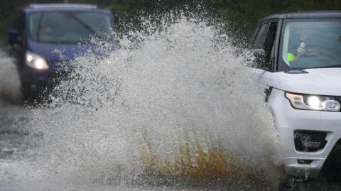 Vehicles travel through areas of flooding.