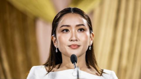 Head and shoulder shot of Paetongtarn Shinawatra, standing in front of a microphone