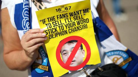 A Sheffield Wednesday supporter holds up an anti-Dejphon Chansiri leaflet before a match