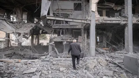 A man walks among the ruins of a commercial-office building affected during military operations in a residential area of Tehran, Iran, on March 29, 2026