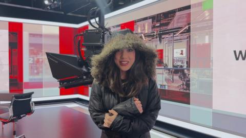 Sabrina Lee stood in the BBC studio wearing a thick black coat with a hood