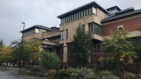 A photo of Sheffield Crown Court, a multi-storey building with pillars either side of the entrance.