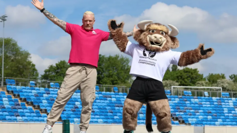 Iwan Thomas and Bab, the official mascot for the championships, jumping in the air in an empty stadium.