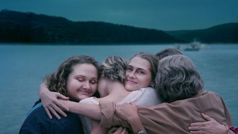 A group of people hugging near a lake