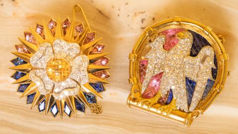 Two diamond-encrusted Cartier brooches depicting a falcon and a white Tudor rose.