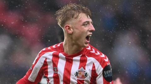 Tommy Watson, while playing for Sunderland, celebrating scoring a goal in a Sunderland red and white striped shirt.