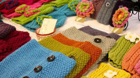 Brightly-coloured home-knitted garments and accessories for sale at a craft fair