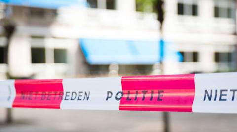 A stock image of white-and-red striped Dutch police tape, which reads 'Politie'.