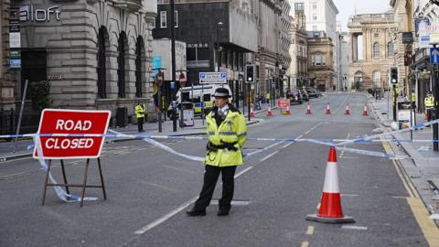 A lone police officer in high visibility uniform guards the scene of the incident in central Liverpool