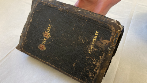 A close-up of Elvis Presley's bible resting on a table with a white cloth on it.