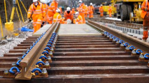 A stock image of people in bright orange PPE on a rail track