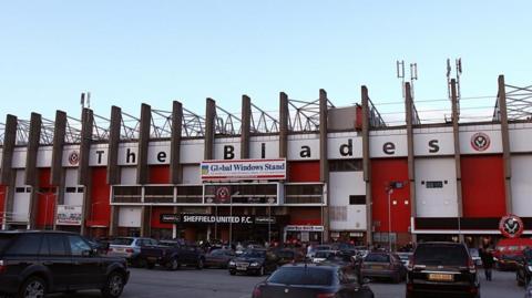 General view of Sheffield United's ground on Bramall Lane, from the outside. "The blades" is printed along the rafters with the club logo either side. Panels are painted alternating red and white.