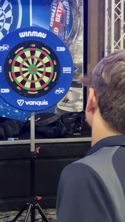 Young boy throwing darts at a dart board