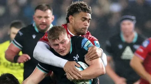 Jac Morgan of Ospreys is tackled by Scarlets' Vaea Fifita