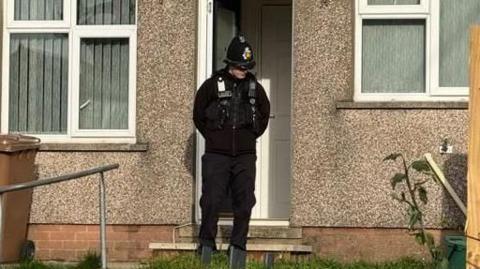 A policeman standing outside a house