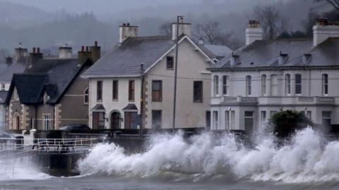 Waves break against the sea wall in Carnlough on the north east coast of Northern Ireland early in the morning of January 24, 2025, as storm Eowyn brings winds of 100 mph to the UK and Ireland