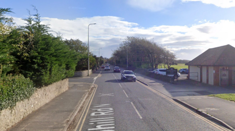 Google Maps street view of Uphill Road in Weston-super-Mare. There is a junction on the left and a building on the ride hand side of the road. There are cars travelling in both directions on the road.