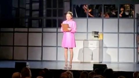 Karla Tracey on stage wearing a pink dress.