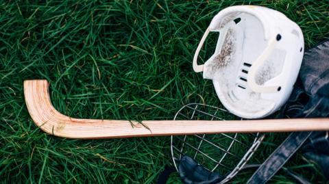 Shinty stick and helmet lying on grass