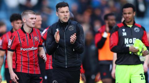 Walsall boss Mat Sadler leads the applause with his squad as they go towards the visiting fans after the 0-0 draw at Gillingham