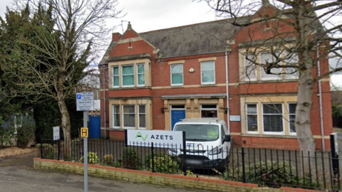 Street view of An Edwardian building with a blue door and a car park in front