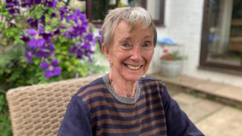 A woman sitting on a chair smiles at the camera