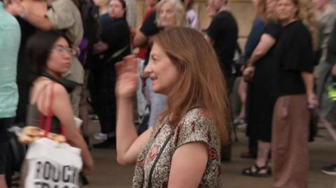 Deborah Prentice - the vice-chancellor of the University of Cambridge - attending a vigil in the city centre. Crowds of people are looking towards her.