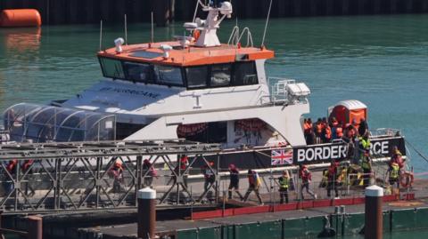A group of people thought to be migrants are brought in to the Border Force compound in Dover, Kent, from a Border Force vessel following a small boat incident in the Channel on 9 September. The people getting off the boat are wearing life jackets. 