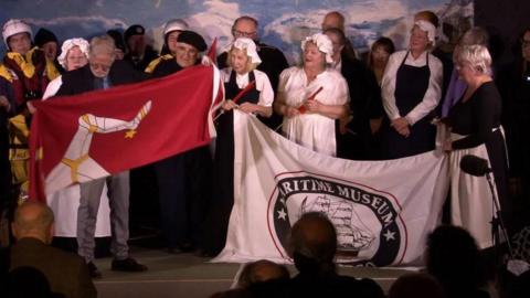 The cast of the show on stage with flags