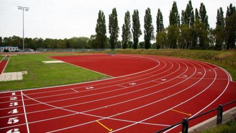 A red race track with trees and grass in the background. 