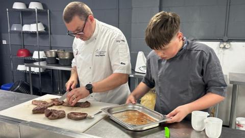 Dexter on the right alongside his father, Greg Olejarka, left chopping up some meat.