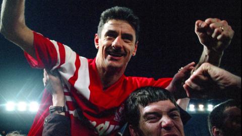 Ian Rush, in a red Liverpool kit, holds his arms aloft as he is carried by supporters off the pitch