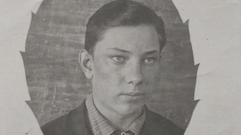 Black and white photo of Vasilii Trushkin. He is young and has short dark hair. He is wearing a striped shirt with a collar. 