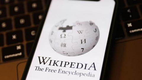 Wikipedia logo displayed on a phone screen and a laptop keyboard are seen in this illustration photo taken in Krakow, Poland on January 19, 2023. (Photo by Jakub Porzycki/NurPhoto via Getty Images)