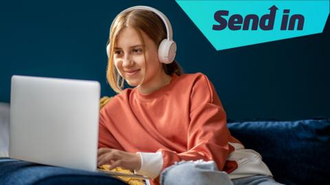 A girl sits on a sofa looking at her laptop and smiling. She is wearing a coral jumper, jeans and a pair of over ear headphones. There is a graphic in the top right corner that says "send in".