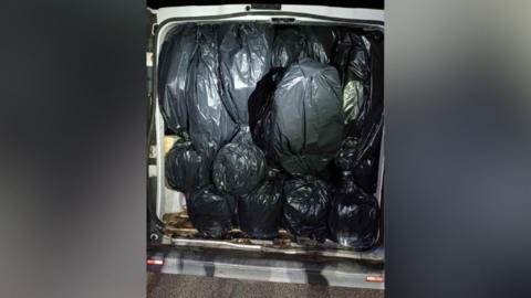 Black bags entirely filling the inside of a white van