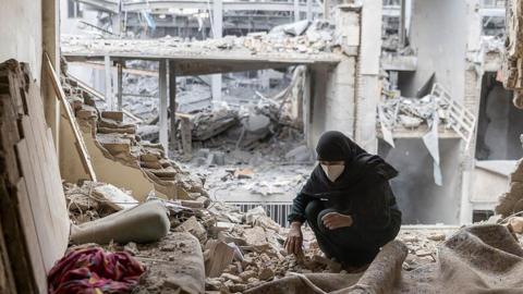 A woman sifts through the rubble in her destroyed flat in Tehran, Iran. Photo: 15 March 2026