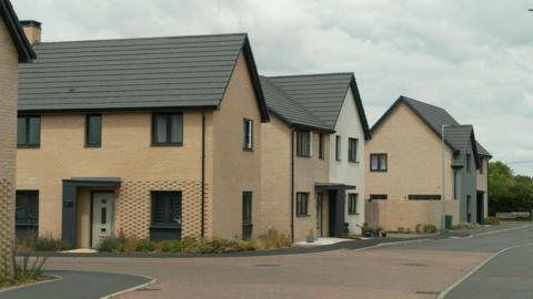 A newbuild housing estate, with four two-storey brick buildings in view