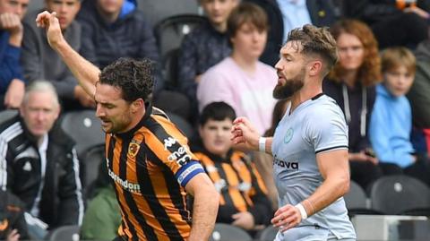 Hull captain Lewie Coyle and Millwall striker Tom Bradshaw tussle for the ball