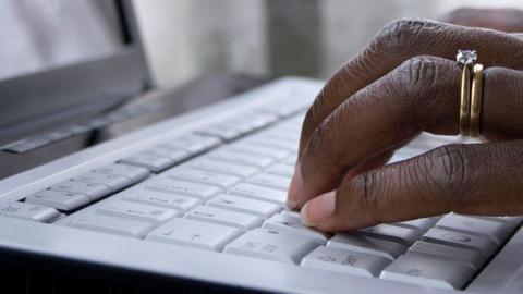 Close-up of a hand resting on the keyboard of a laptop