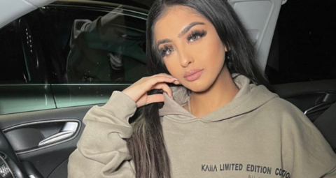 Woman with long brown hair in a car wearing a hoodie.