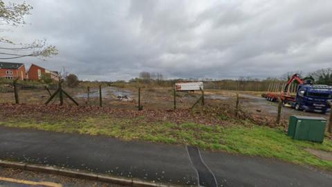 A patch of derelict land viewed from the road nearby