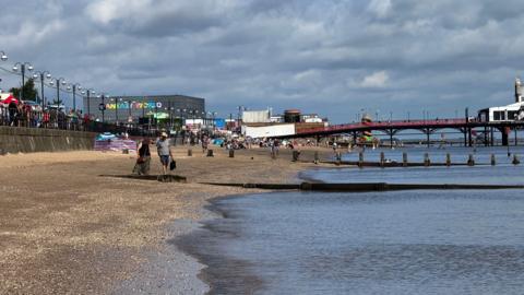 A view of the beach from the point where the sea meets the beach. The pier is in the distance and the Fantasy World building with it's multicoloured lettering is to the left of the frame.