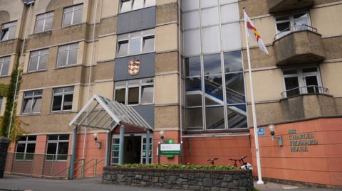 Sir Charles Frossard House - a large yellow building, often referred to as Custard Castle, with a Guernsey flag outside it.
