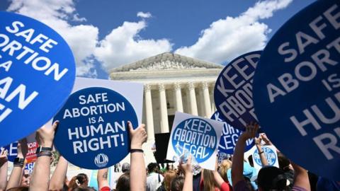 Protesters hold signs outside the Supreme Court