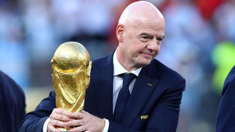 Gianni Infantino with his hands around the men's World Cup trophy