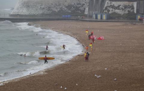 Viking Bay in wet and windy weather, with a few surfers coming out of the water