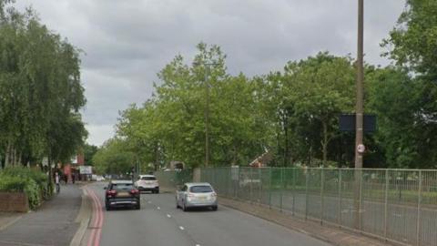 A two lane road with cars driving away from the camera